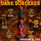 A fantasy-themed novelty item, the Creature Cocks Mephisto - Red/Black 18.5 cm Fantasy Dildo stands centrally against a fiery background with icons labeled Premium Silicone, Phthalate-Free, Creature Fantasy, and Strong Suction Base. Perfect for any Mephisto-inspired adventure.