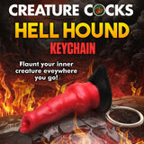 A red, sculpted keychain resembling a mythical horn with black details is set against a fiery backdrop. It reads Creature Cocks Hell-Hound Keychain - Novelty Fantasy Dildo Keyring, inviting you to flaunt your inner creature and embrace fantasy roleplay everywhere!.