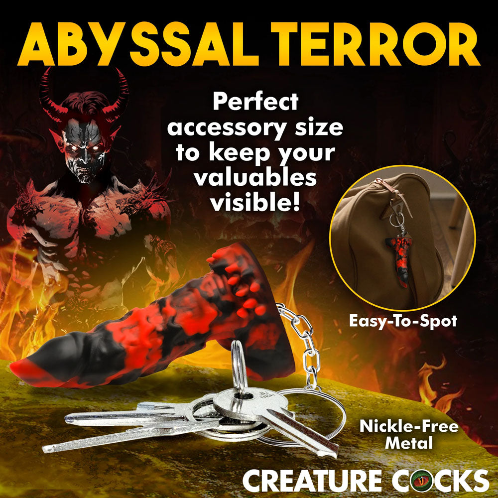 The red and black horn-shaped Creature Cocks Fire Demon Keychain boldly displays ABYSSAL TERROR atop a demonic background, ideal for fantasy roleplay fans. Perfectly sized to keep your keys visible on any adventure!.