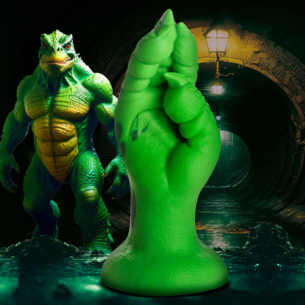 Under a glowing lamp in a dark tunnel, the Creature Cocks Raptor Claw Fisting Silicone Dildo showcases its green, humanoid lizard design with a yellow chest, spiky head, muscular build, and detailed massive hand with sharp talons—ideal for fantasy roleplay.