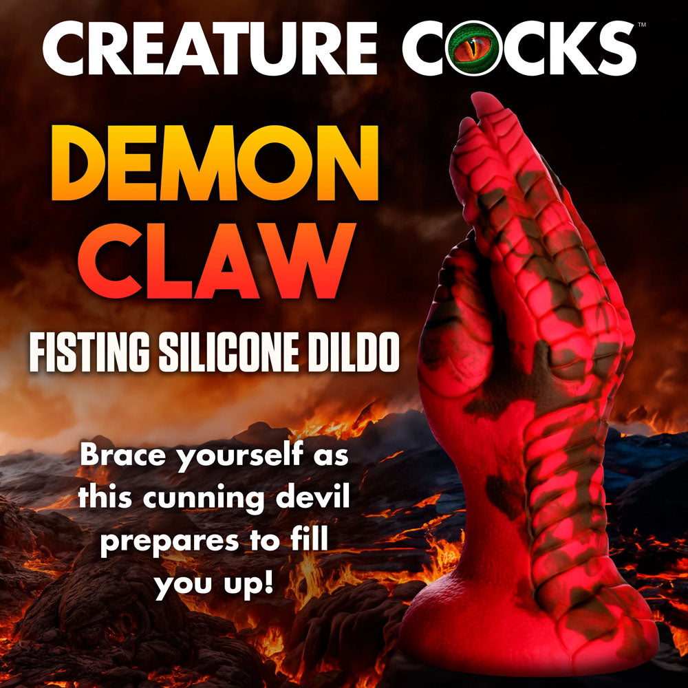 A red and black claw-shaped silicone dildo is set against a fiery background. Text reads: “Creature Cocks Demon Claw Fisting Silicone Dildo - Red 21.8 cm Claw Fantasy Dildo. Embrace fantasy roleplay with this demonic hand design as the cunning devil prepares to fill you up!”.