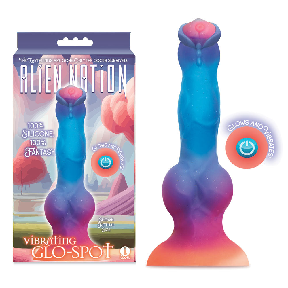 The Alien Nation - Glo-Spot is a 21.6 cm glow-in-the-dark fantasy dong with a soothing blue-to-pink gradient, rounded base, and powerful vibrations. Its whimsical box features an alien landscape, highlighting its glowing silicone material and USB rechargeable capabilities.
