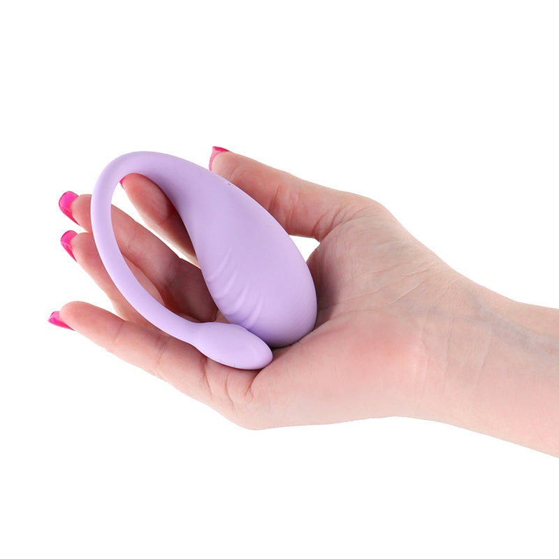 A hand with pink nails holds the Techno - Rave - Purple USB Rechargeable Vibrator, enhanced with an insertable vibe. This oval-shaped, water-resistant device features a flexible tail for pelvic floor exercises and shines against the plain white background.