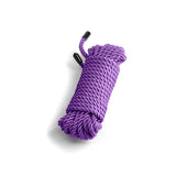 The Bound Rope - Purple is a 7.6-meter purple polyester rope with non-chaffing, tightly woven fibers and black plastic-capped ends, creating a smooth texture. Neatly coiled on a white background, shadows to the left enhance its three-dimensional appearance.