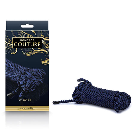The Bondage Couture Rope - Blue set features a sleek blue rope with shiny metal tips, housed in an elegant gold and black box displaying NS Novelties. It rests stylishly on a white surface.
