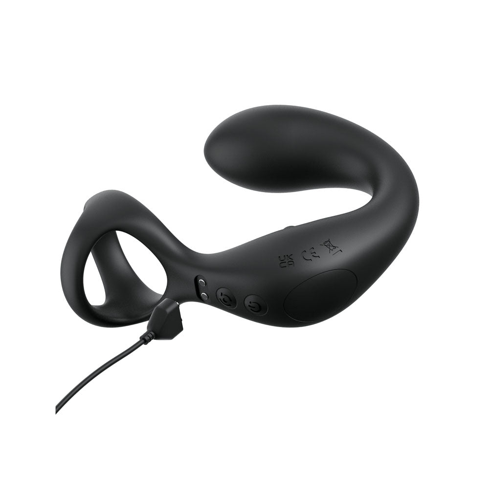 The Anal Fantasy Elite Ass-Gasm Taint-alizer, a black curved wearable device, is set against a white backdrop. It showcases a looped handle and smooth contours for perineum stimulation, with visible buttons for power and settings on the side. A cord connects to its charging port for USB recharging.