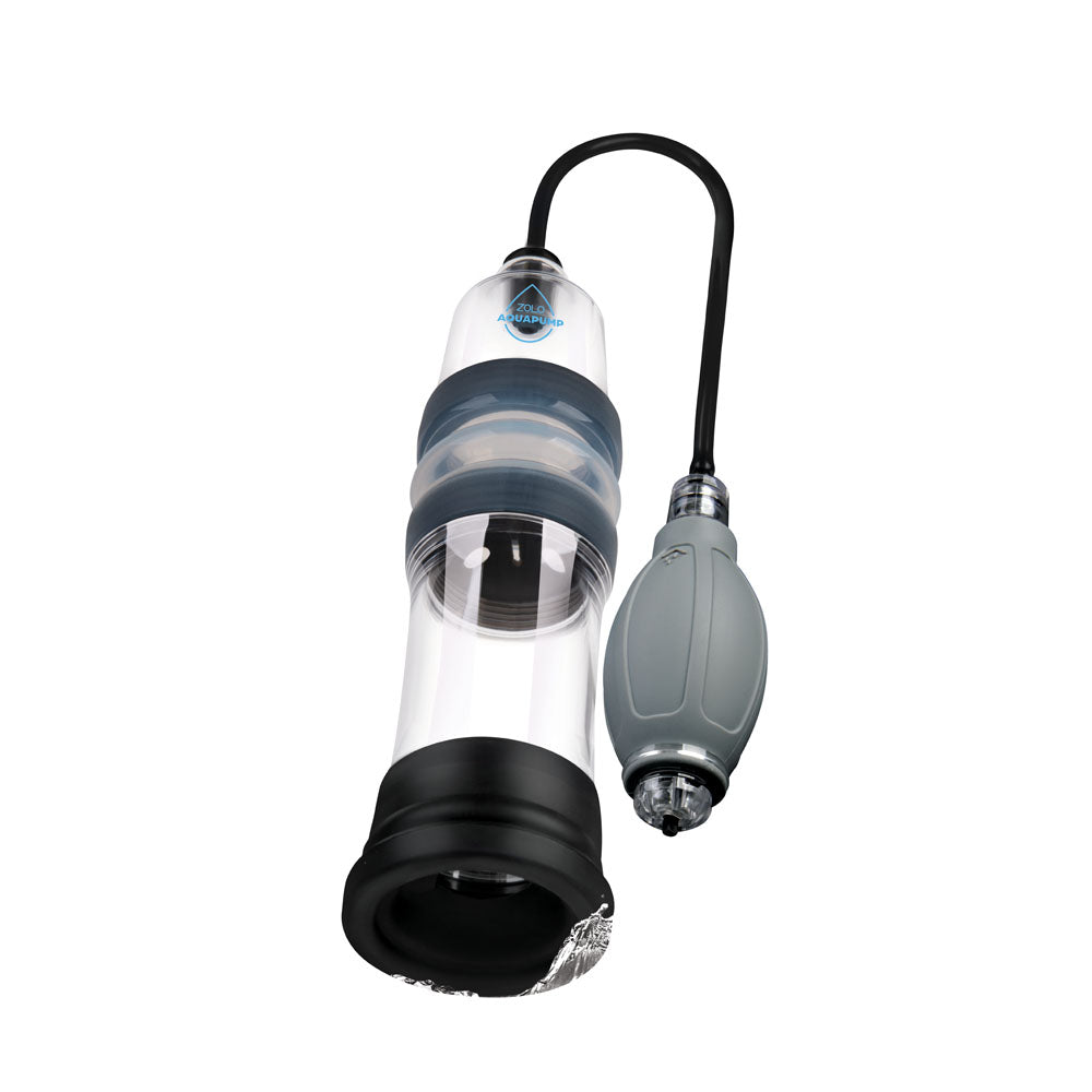 The Zolo Aquapump Compact - Clear Water Penis Pump, features a clear cylindrical design with a black base and grey rubber bulb handle. A tube connects the manual pump, featuring ridged grips and a dark middle band, topped with the logo against a white background.