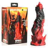 The Creature Cocks Mephisto Red/Black 18.5 cm Fantasy Dildo, in premium silicone with a flame-like design, sits beside its box with a fiery background and horned demon, offering an otherworldly allure.