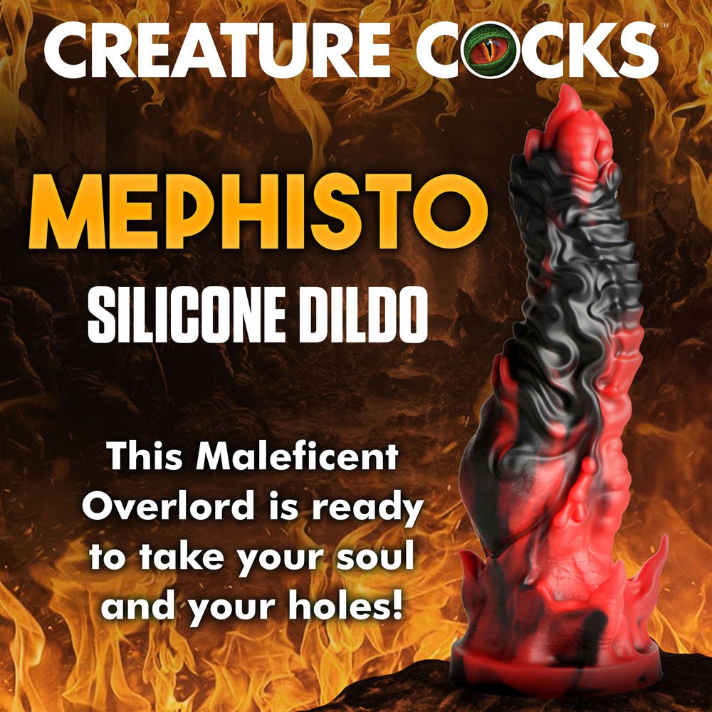 The Creature Cocks Mephisto Dildo, in fiery red and black premium silicone, is set against a blazing backdrop with the text: CREATURE COCKS, SILICONE DILDO. Let this Maleficent Overlord capture your soul and your senses!.