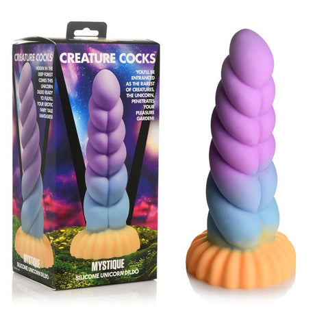 A Creature Cocks Mystique Silicone Unicorn Dildo features a colorful spiral of purple, blue, and pastel orange on a flared suction cup base. Displayed in a vibrant box, it is promoted as the 21 cm premium fantasy dildo.