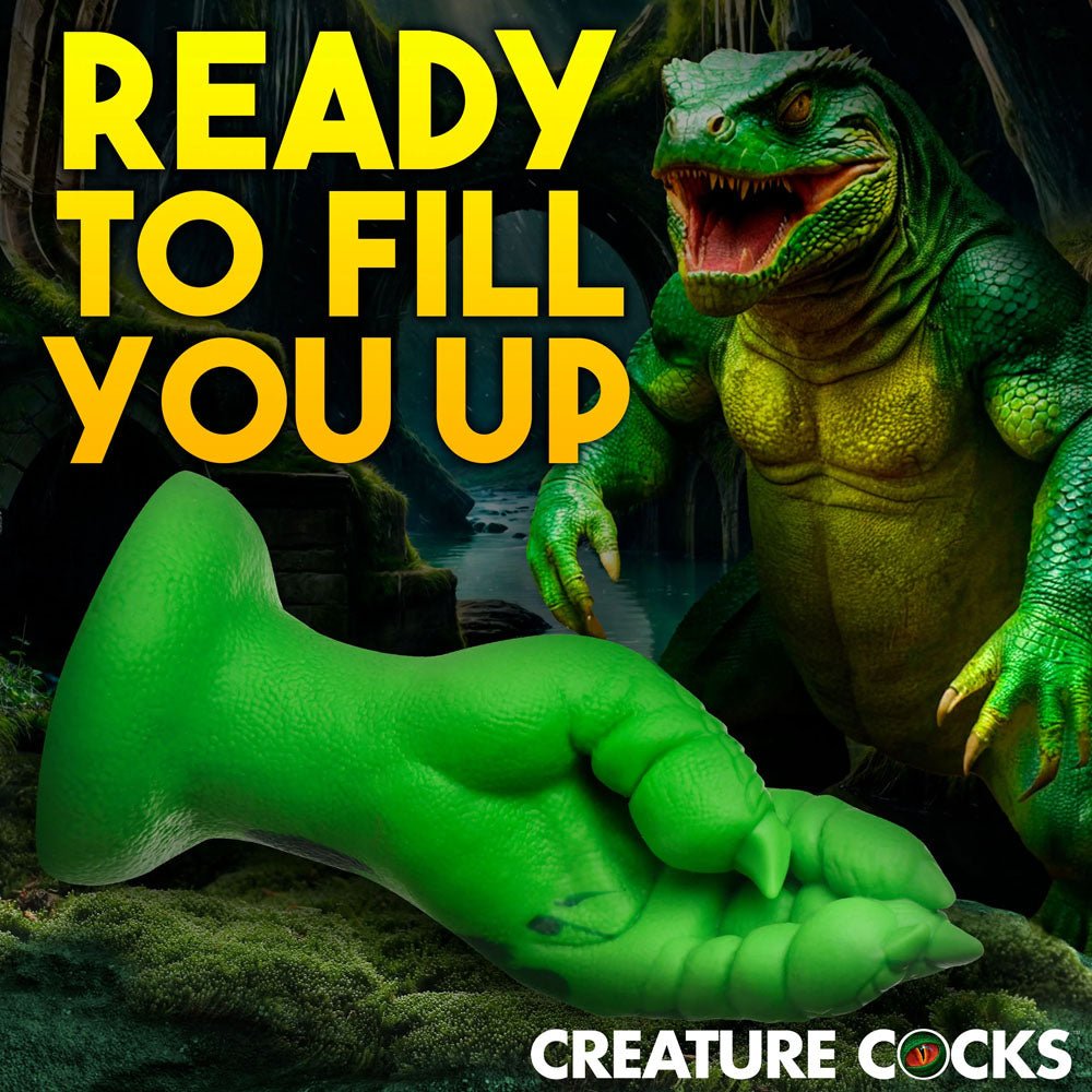 In the dark forest, a fantasy creature with green and yellow scales looms. In the foreground lies a Creature Cocks Raptor Claw Fisting Silicone Dildo - Green 21.8 cm Claw Fantasy Dildo, inviting you into a world of fantasy roleplay with READY TO FILL YOU UP blazing above.